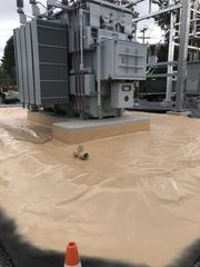 A person wearing yellow gloves is spraying powder paint on a piece of metal.