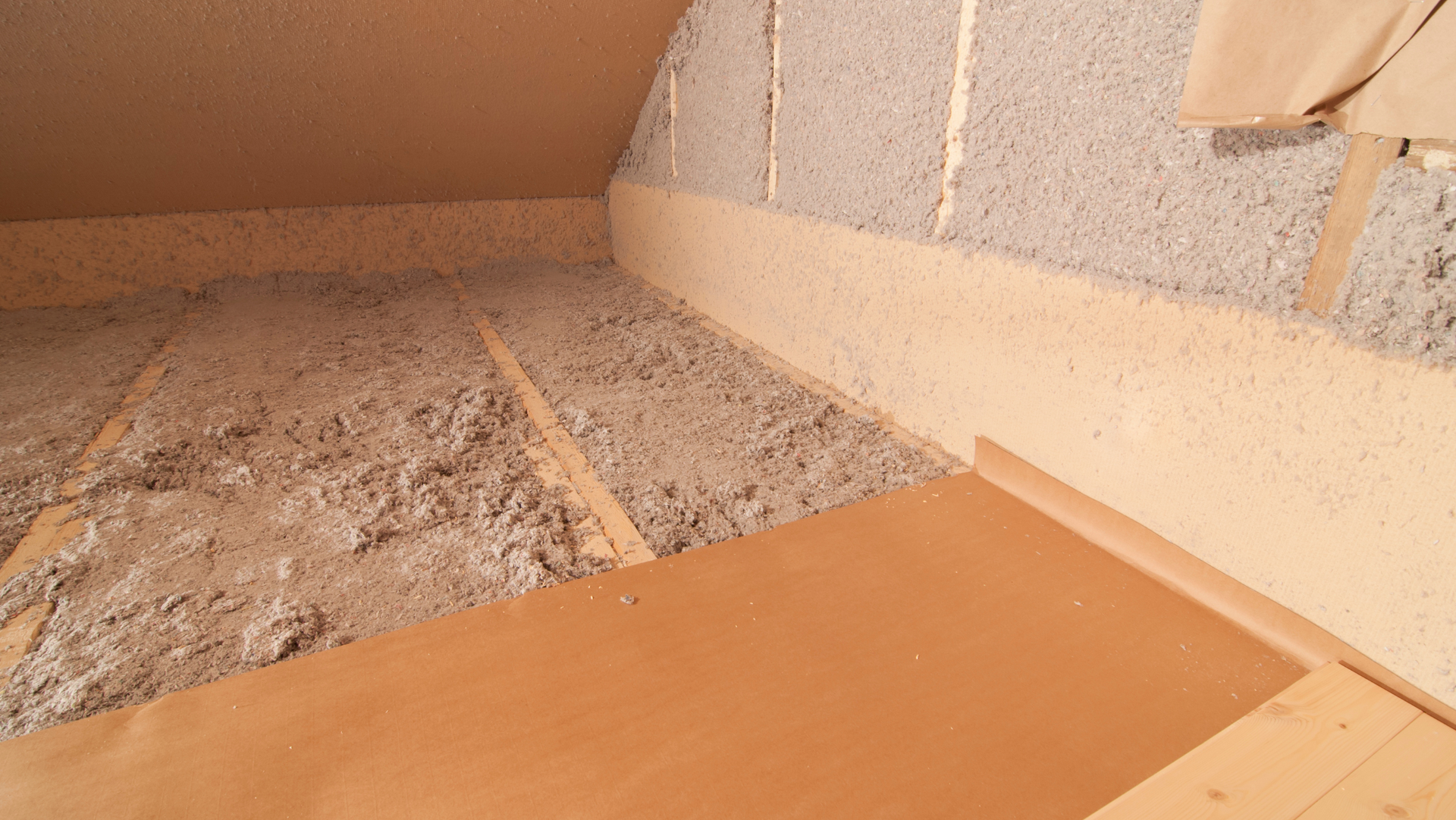 An attic with a wooden floor and a lot of insulation on the floor.