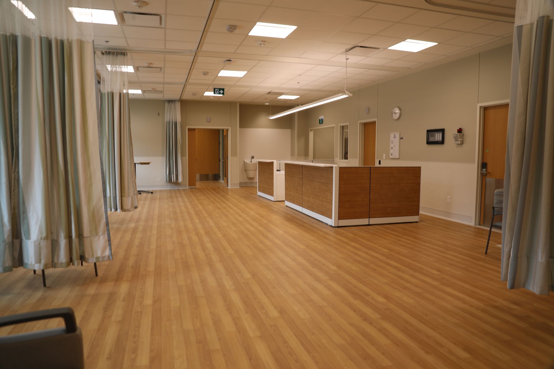 An empty hospital room with wooden floors and curtains.
