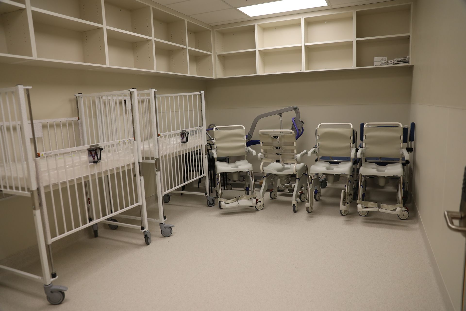 A room with a row of hospital beds and chairs.