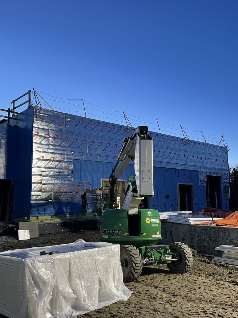 A green crane is sitting in front of a building under construction.