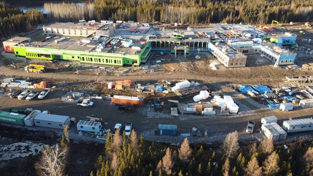 An aerial view of a large building under construction in the middle of a forest.