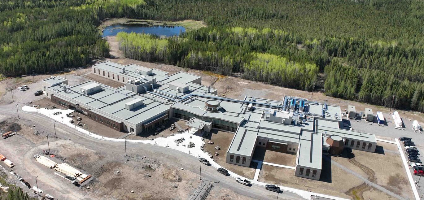 An aerial view of a large building under construction in the middle of a forest.