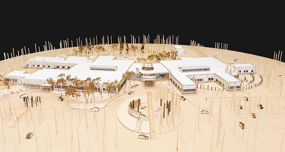 A model of a large building in the middle of a forest.