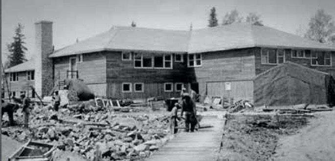 A black and white photo of a large house under construction.