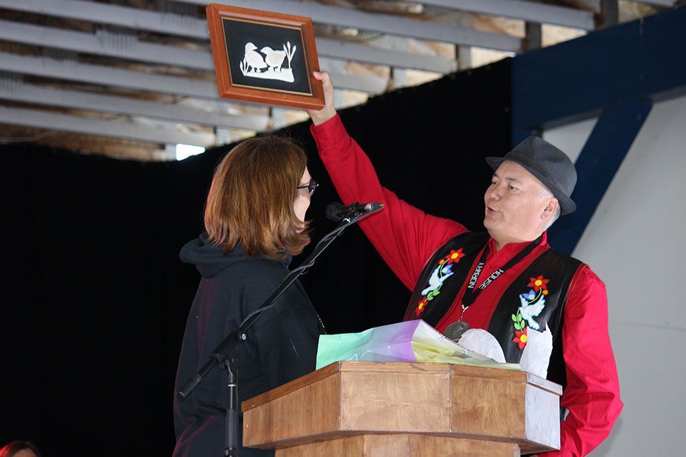 A man is giving a plaque to a woman at a podium.