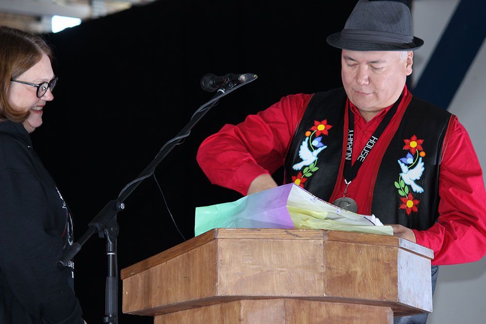 A man in a hat is standing at a podium talking to a woman.
