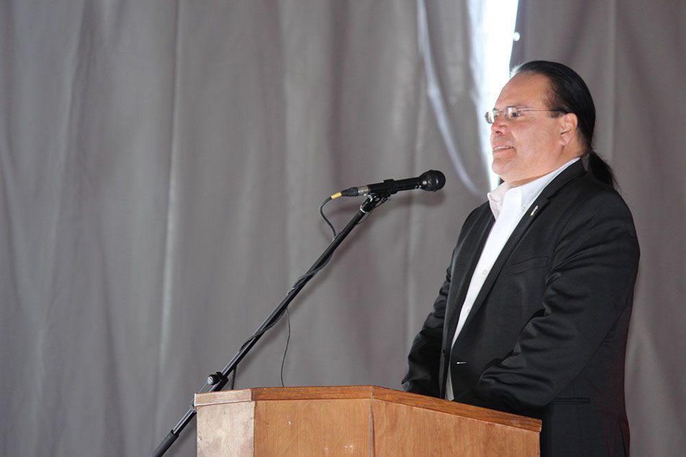 A man in a suit is standing at a podium speaking into a microphone.