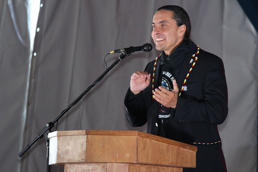 A man is standing at a podium speaking into a microphone.