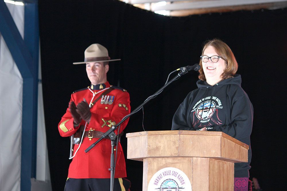 A woman stands at a podium next to a man in a uniform