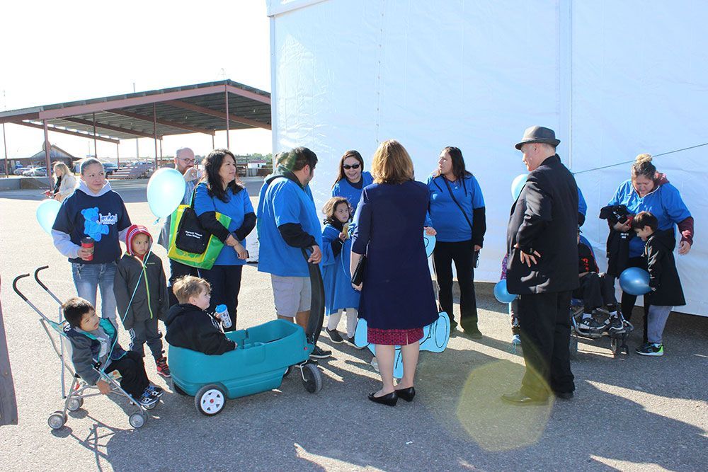 A group of people are standing around a blue wagon with a child in it.