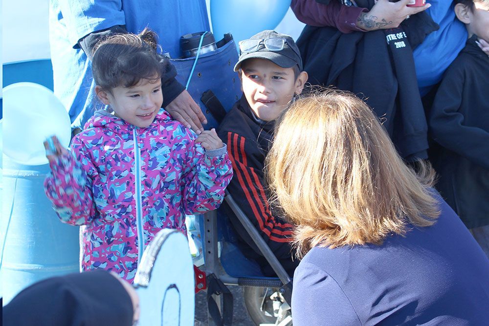A woman is taking a picture of a little girl in a pink jacket