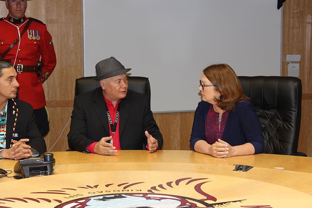 Two men and a woman are sitting at a table talking to each other.