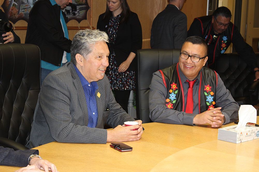 Two men are sitting at a table talking to each other.