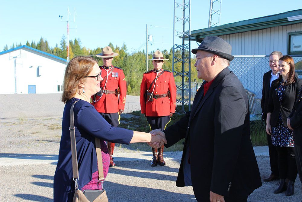 A man and a woman are shaking hands in front of a group of soldiers.