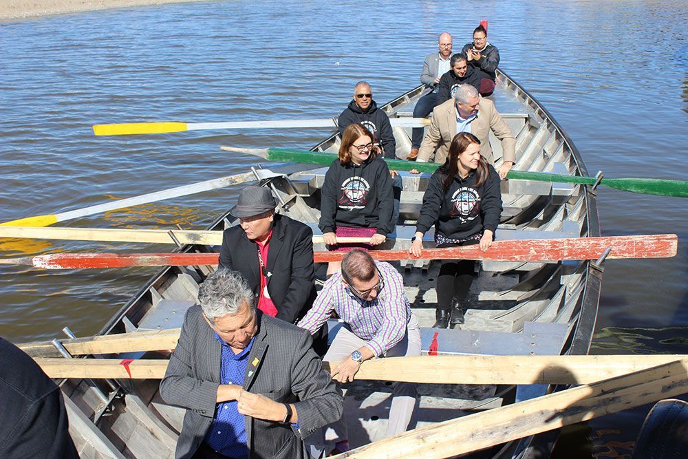 A group of people are rowing a boat in the water.