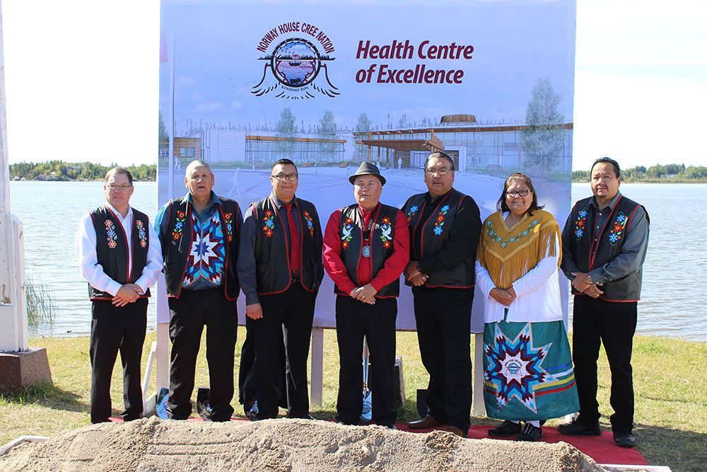 A group of people standing in front of a sign that says health centre of excellence.