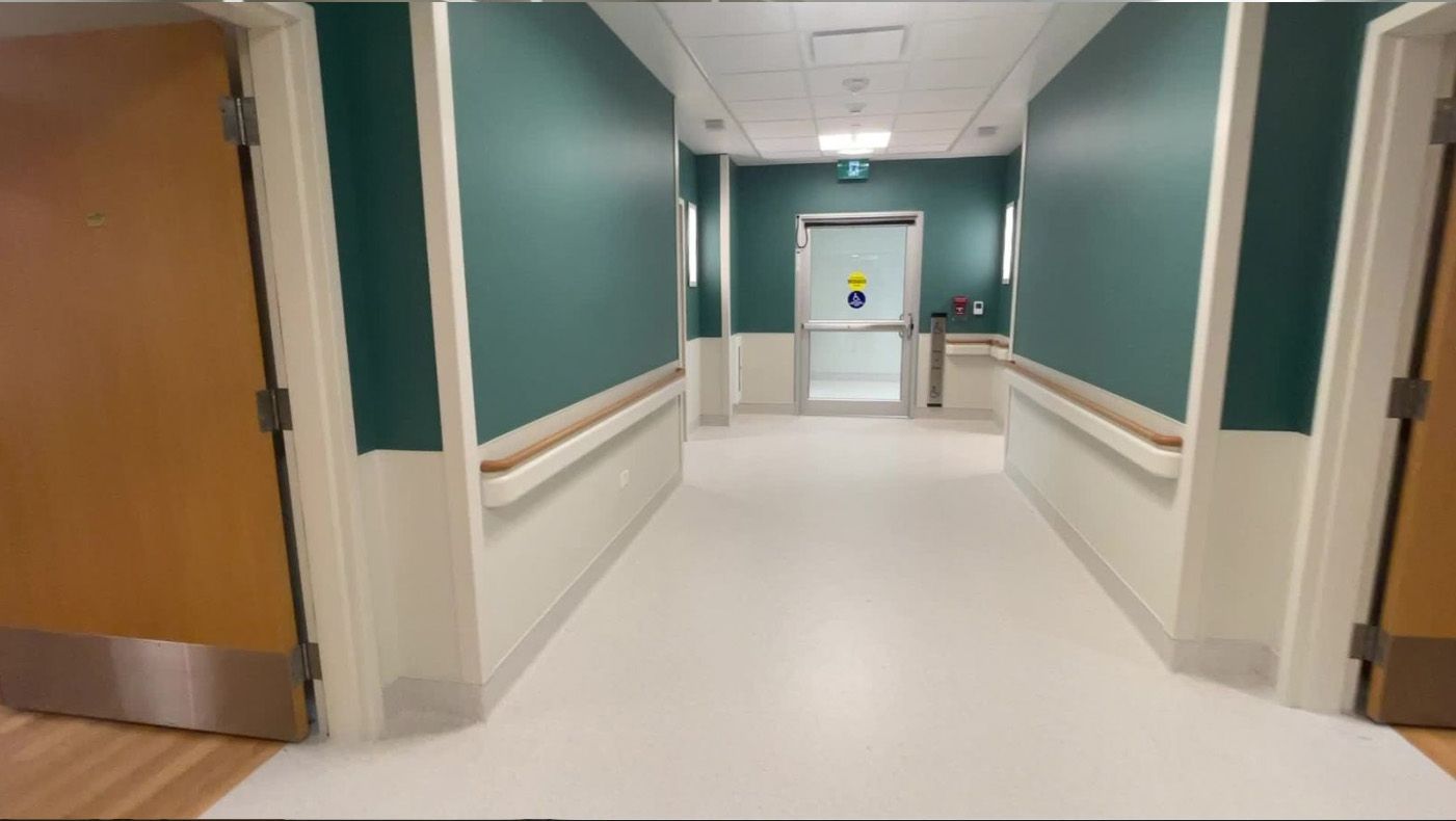 A hospital hallway with green walls and white floors