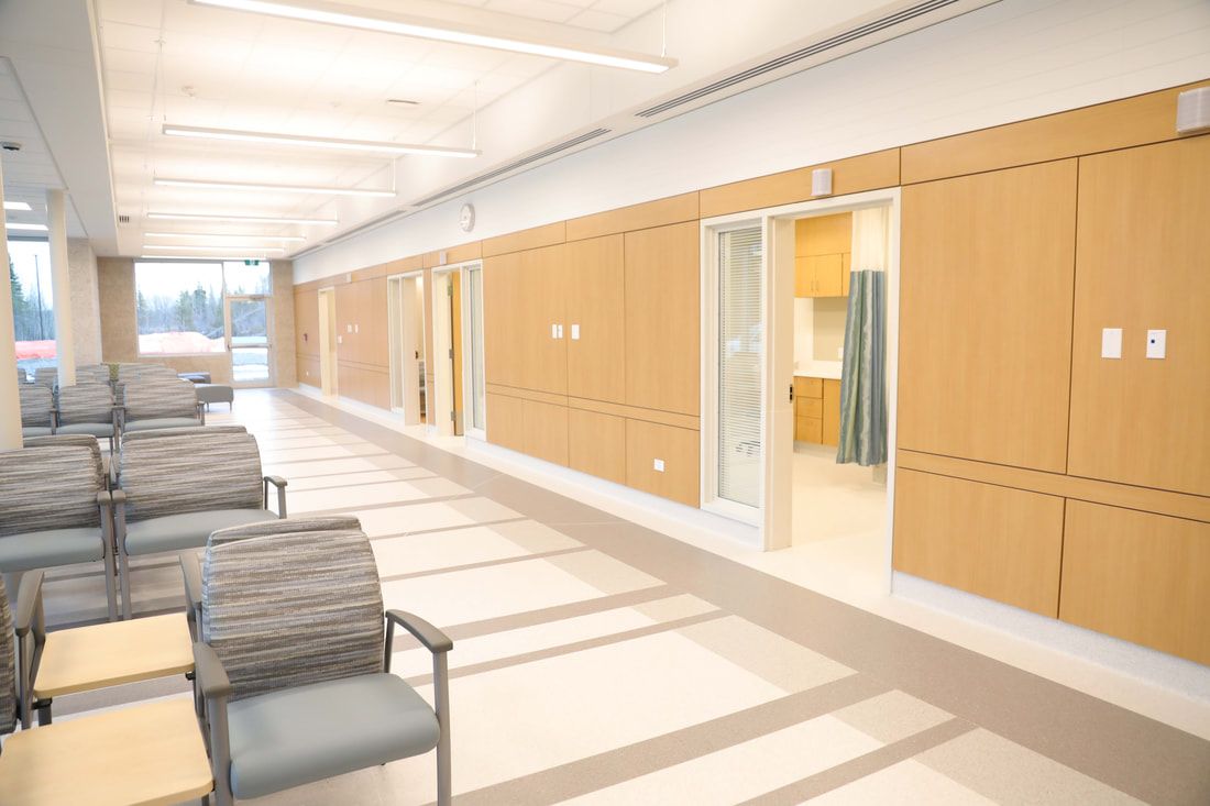 A long hallway in a hospital with chairs and tables.