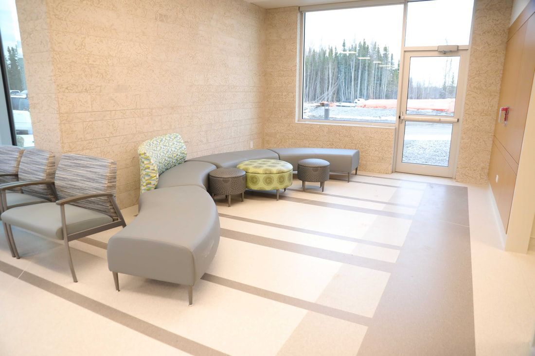 A waiting room with a couch , chairs , and a window.
