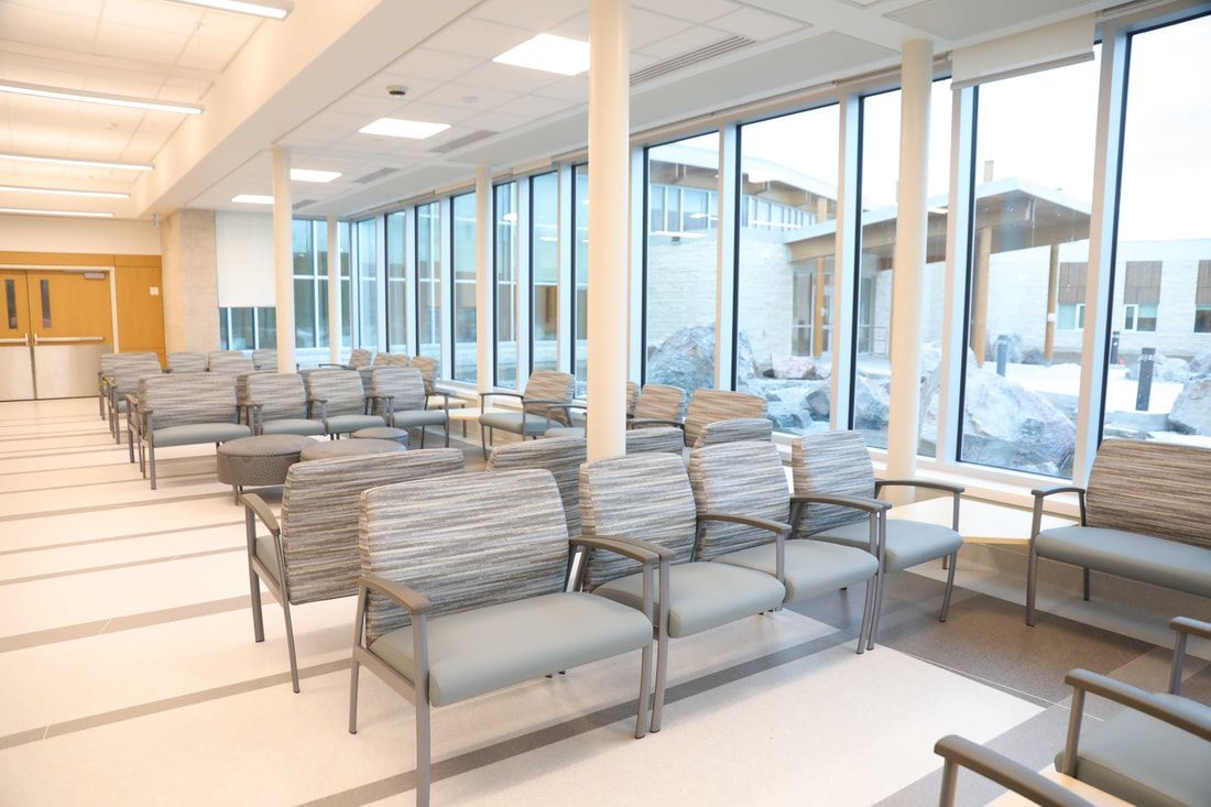 A waiting room in a hospital with lots of chairs and windows.