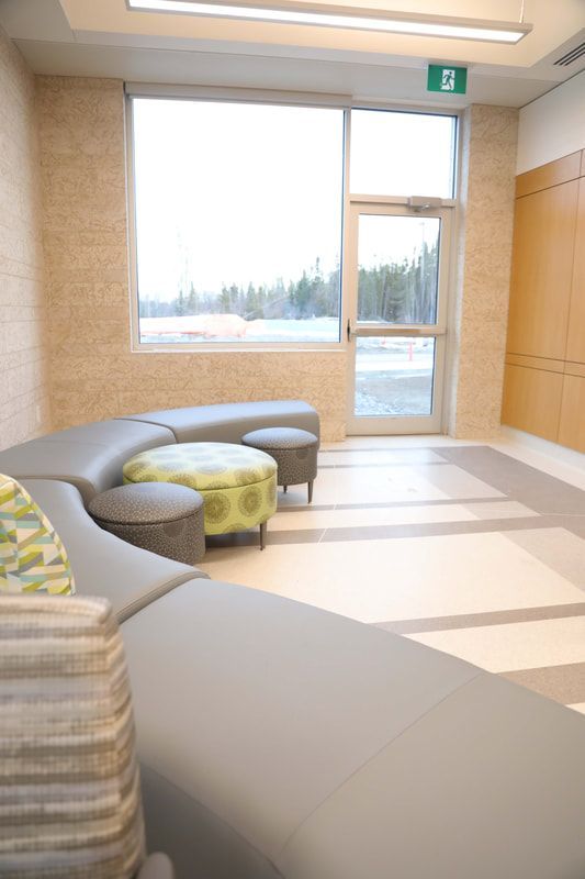 A room with a couch and ottomans and a window