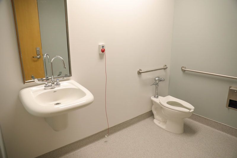 A bathroom with a toilet , sink and mirror.