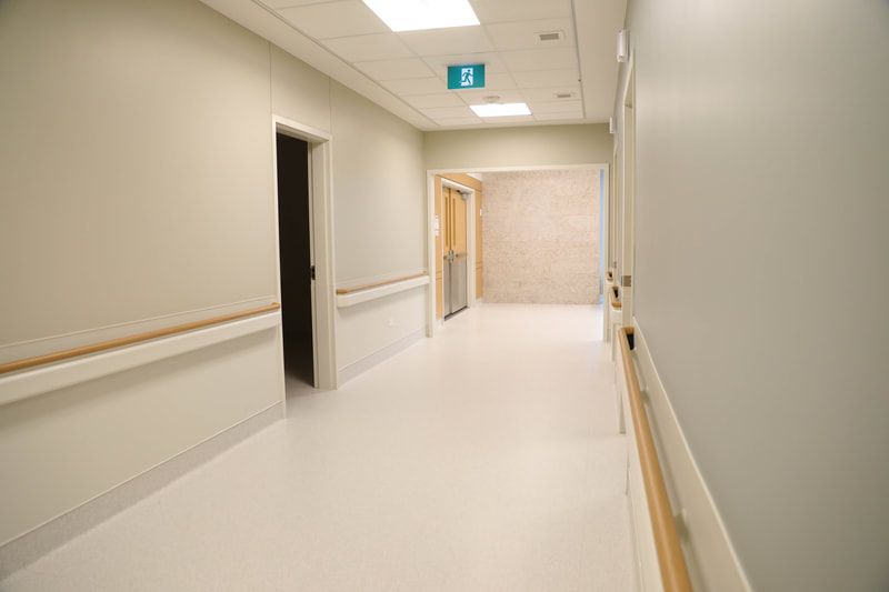 An empty hospital hallway with a wooden handrail and a door.