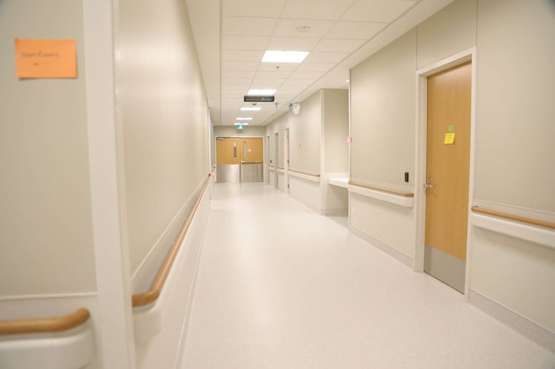 An empty hospital hallway with a sign on the wall that says ' emergency room '