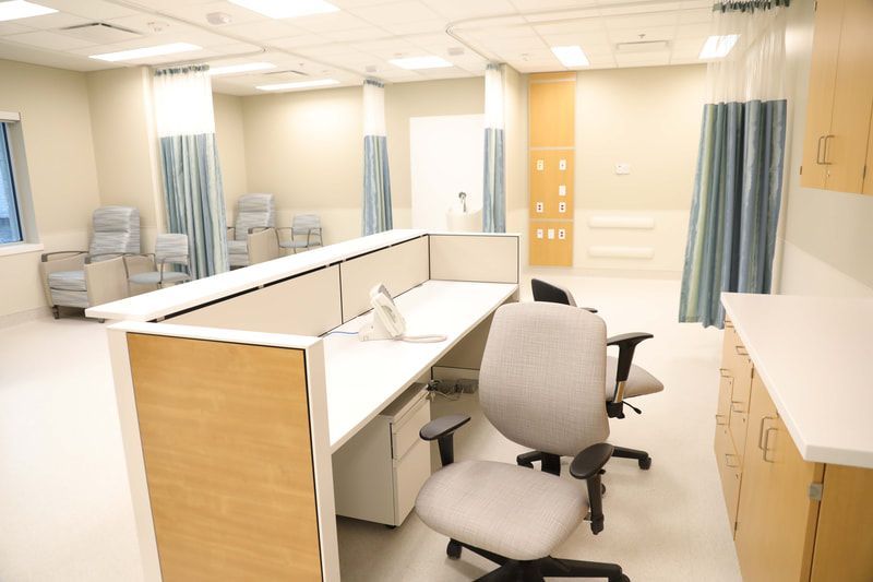 A cubicle in a hospital with a desk and chairs