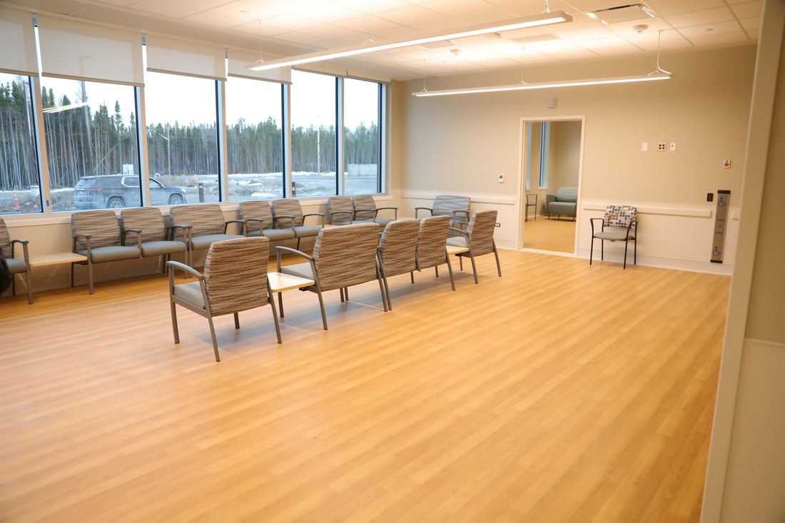 A large waiting room with a lot of chairs and windows.