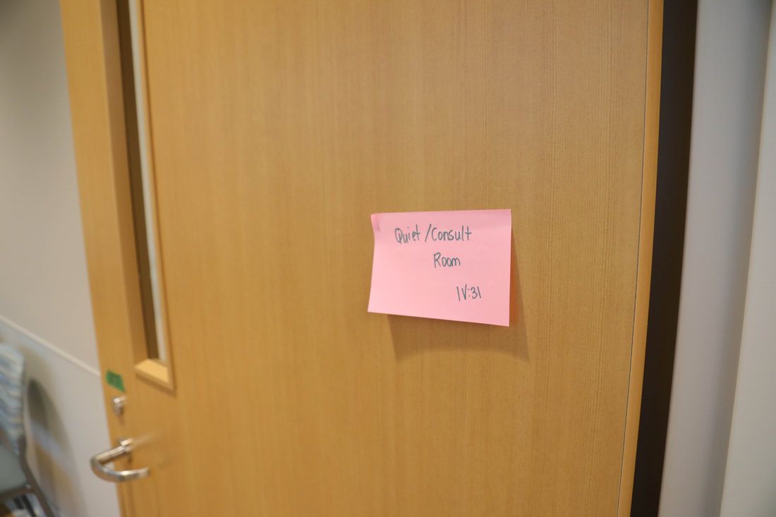 A wooden door with a pink sticky note on it