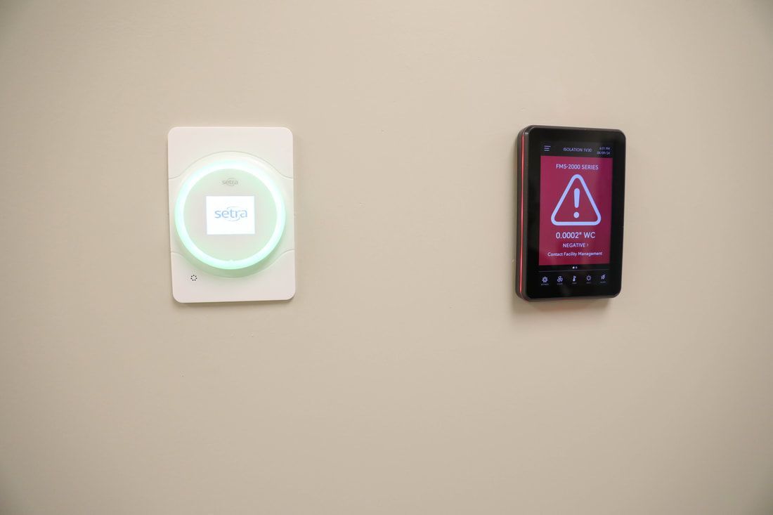A thermostat and a smart phone are hanging on a wall.
