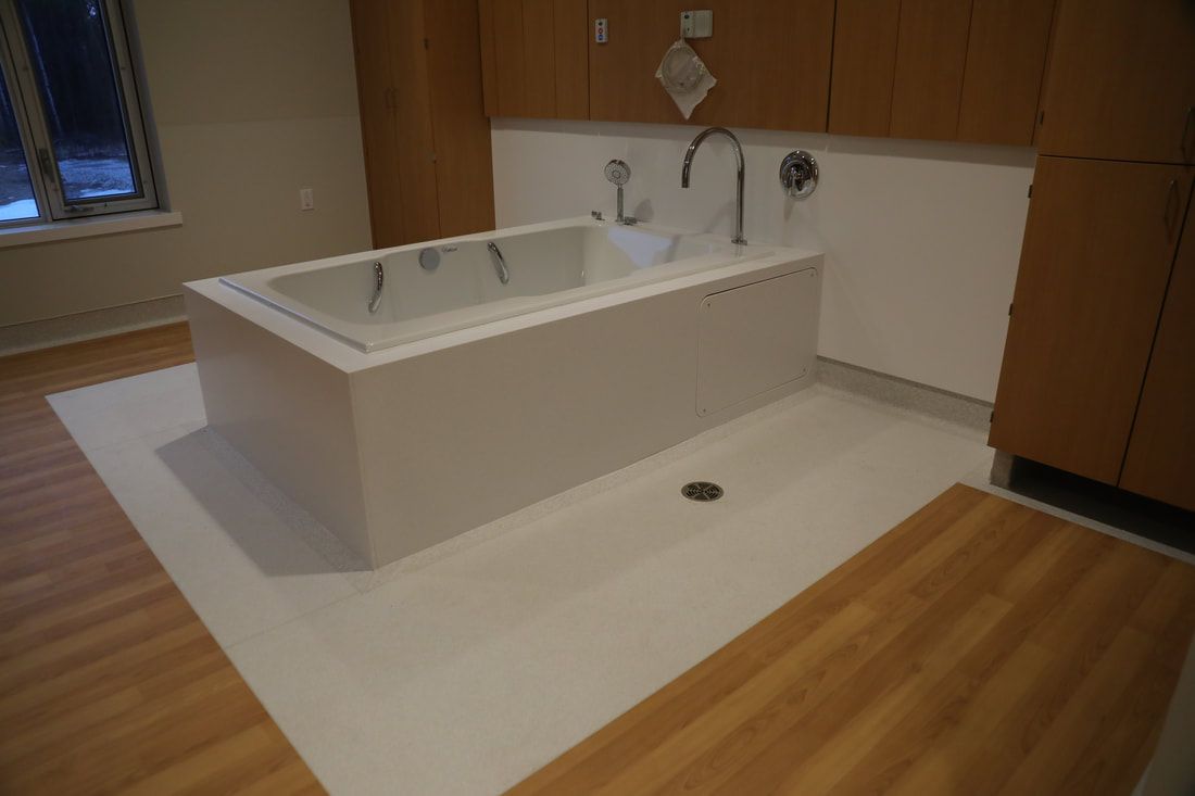 A bathtub is sitting on a wooden floor in a bathroom.