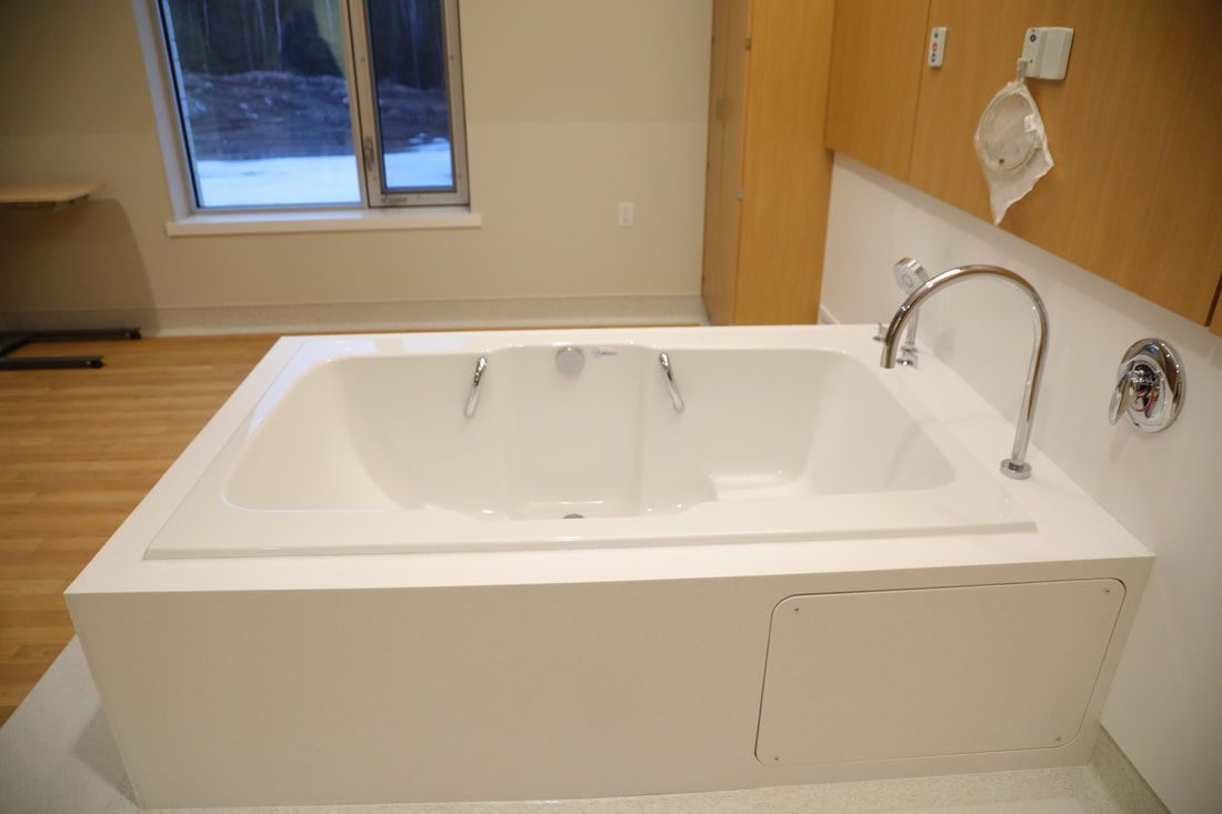 A white bathtub with a faucet in a bathroom next to a window.