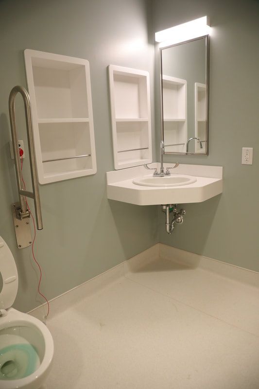 A bathroom with a toilet , sink , mirror and shelves.