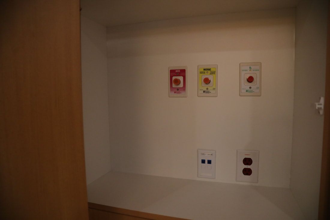 A white wall with three electrical outlets and three buttons on it.
