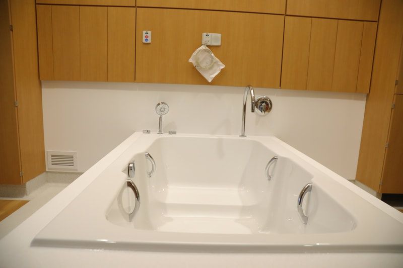 A large white bathtub in a bathroom with wooden cabinets