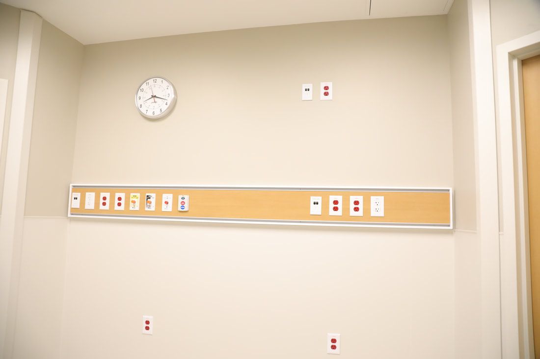 An empty hospital room with a clock on the wall.