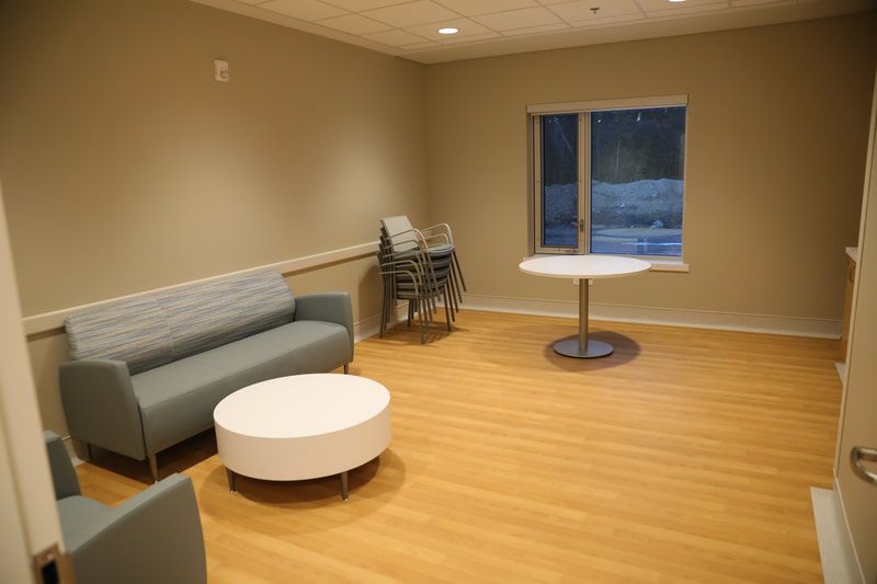 A living room with a couch , table , chairs and a window.
