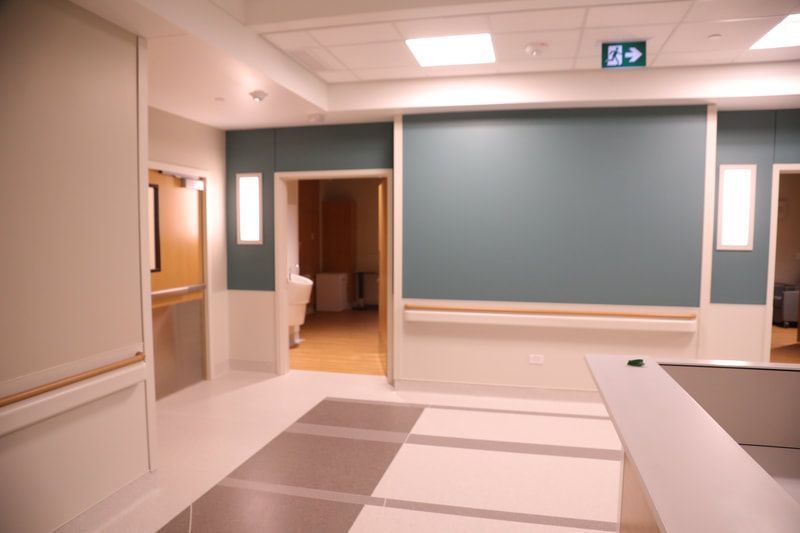 A hospital hallway with a blue exit sign on the ceiling