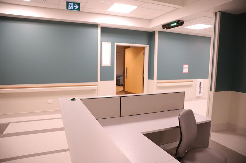 A hospital hallway with a desk and a chair