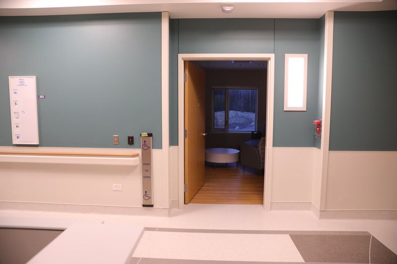 A hospital room with blue walls and a door that is open.