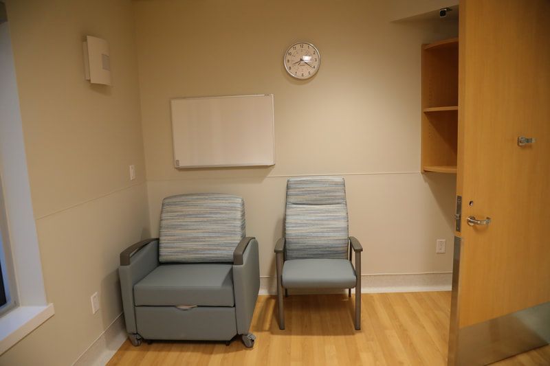 A room with two chairs and a clock on the wall.