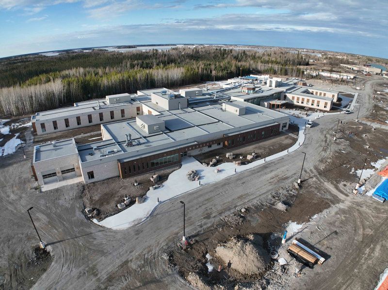An aerial view of a large building under construction in the middle of a dirt field.