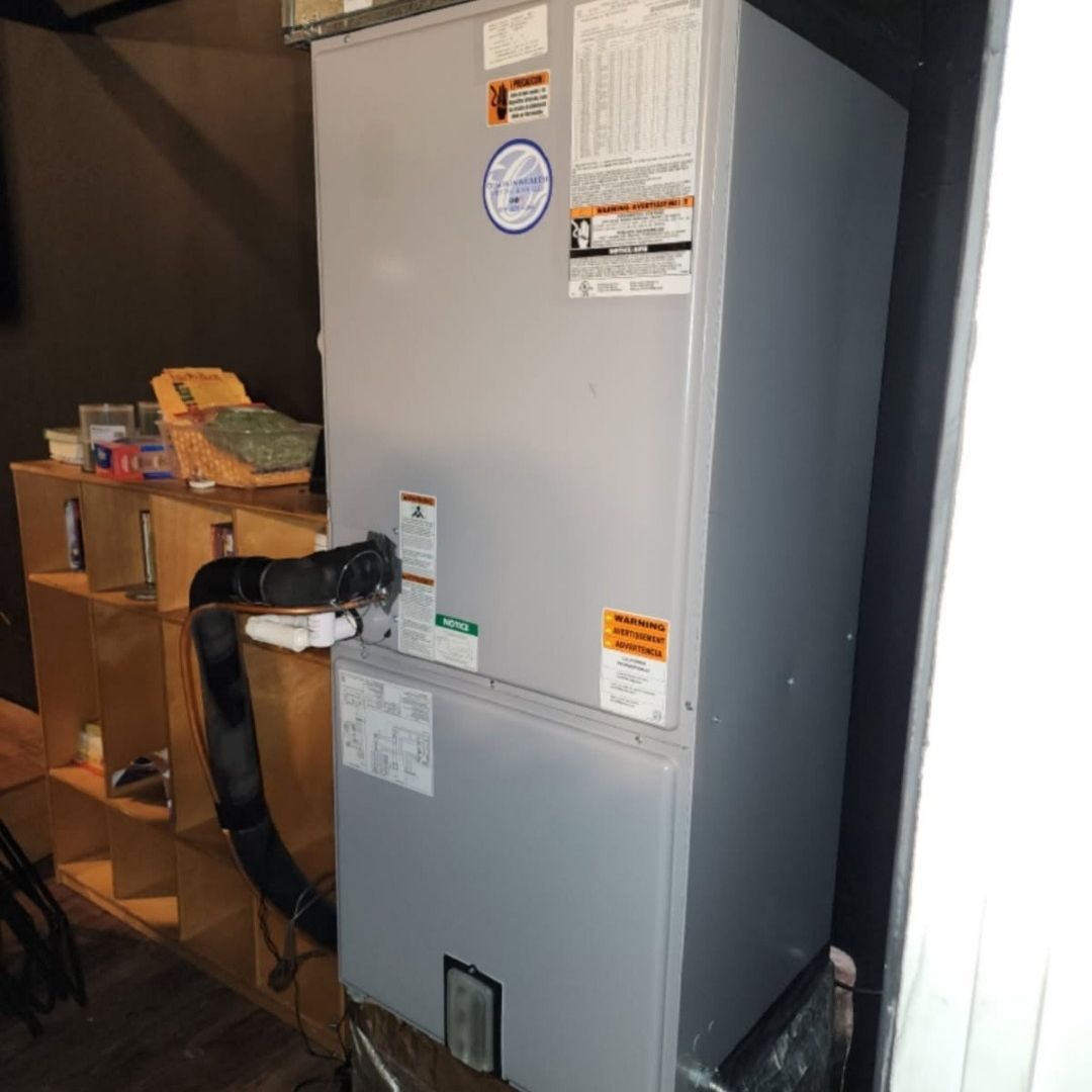 A gray refrigerator is sitting in a room next to a wooden shelf