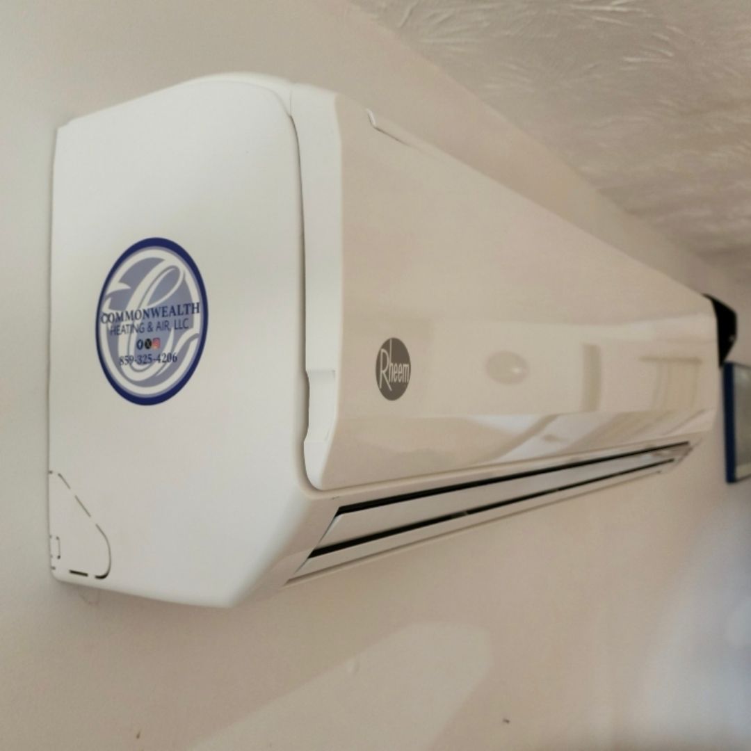 A white air conditioner is hanging on a white wall