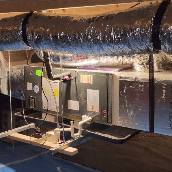 An air conditioner is sitting under a table in a room.
