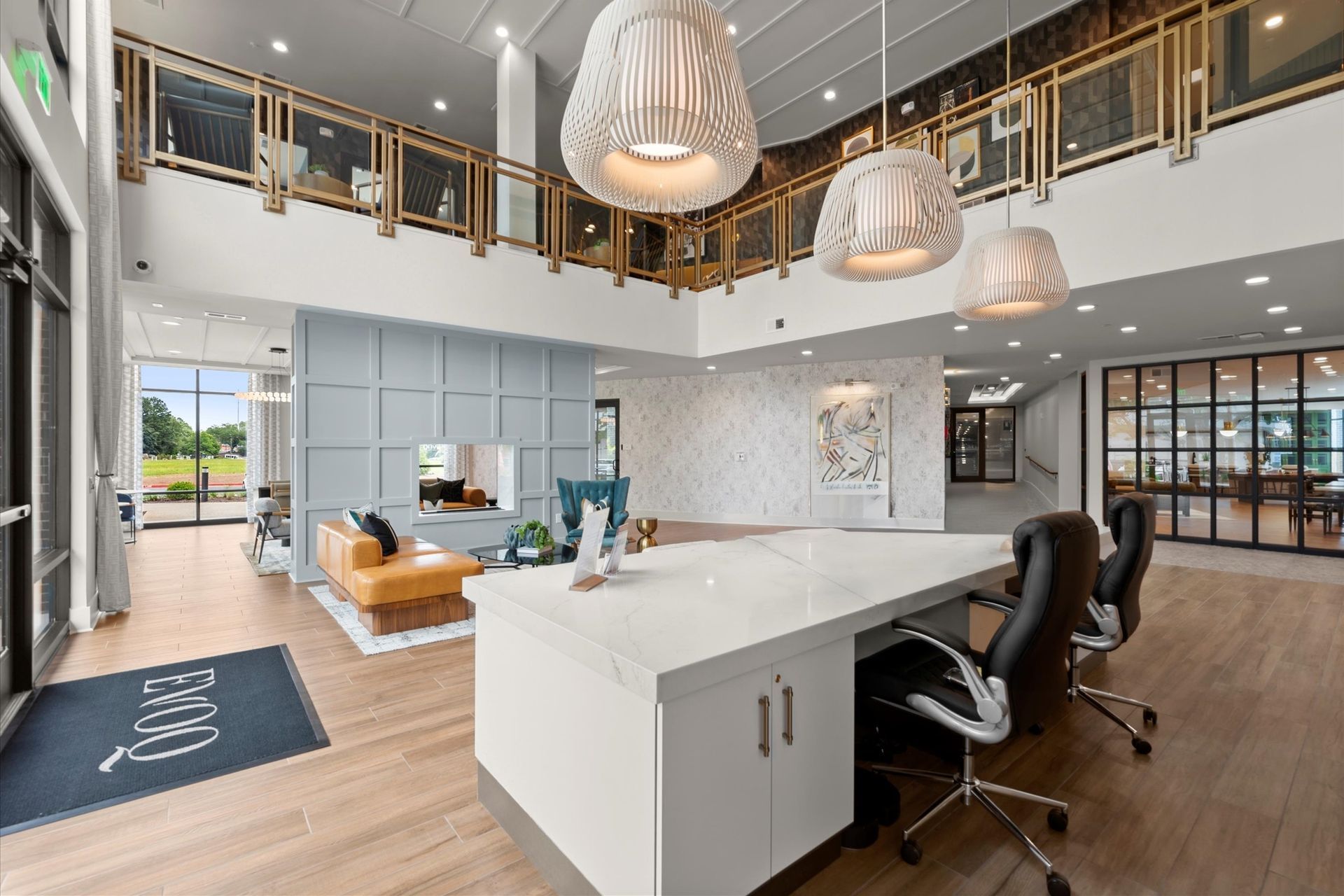 Modern office lobby with a white reception desk, decorative lights, and seating area.