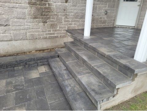 Stone steps leading up to a porch with brick facade and white columns.